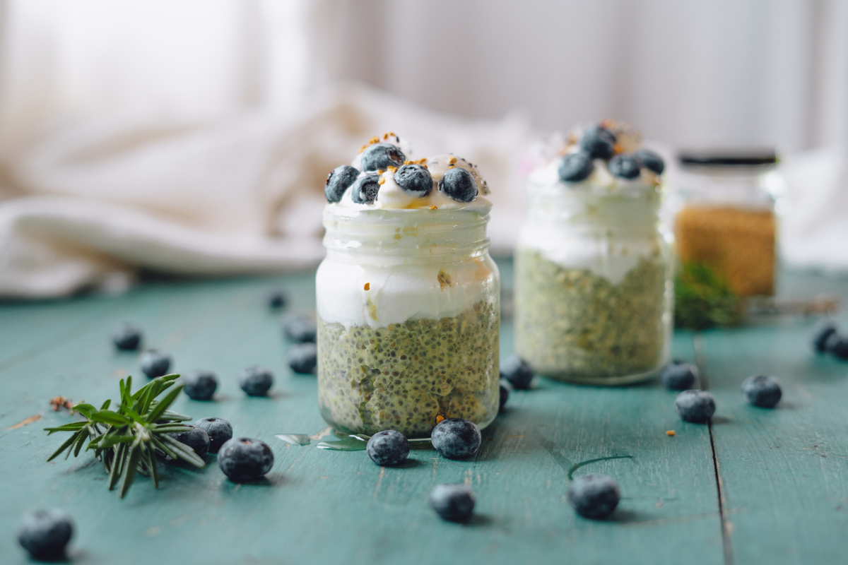 Seasoning Quinoa Parfait: A jar of quinoa layered with creamy yogurt and topped with fresh blueberries and a sprinkle of bee pollen on a teal table.