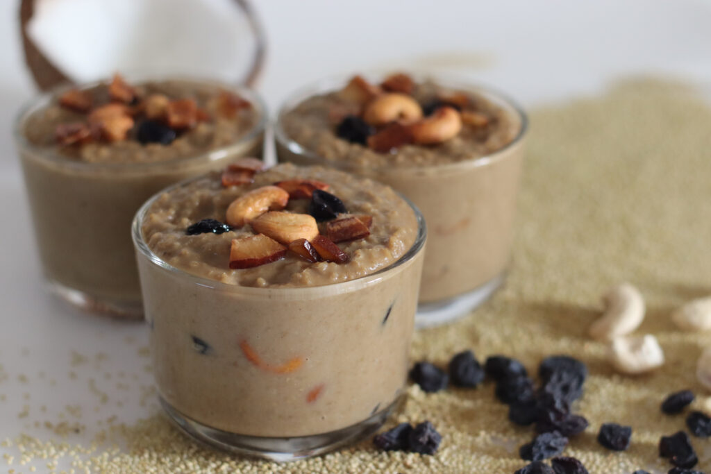 Quinoa dessert recipe featuring creamy quinoa pudding topped with nuts and dried fruit, alongside raw quinoa grains and cashews.