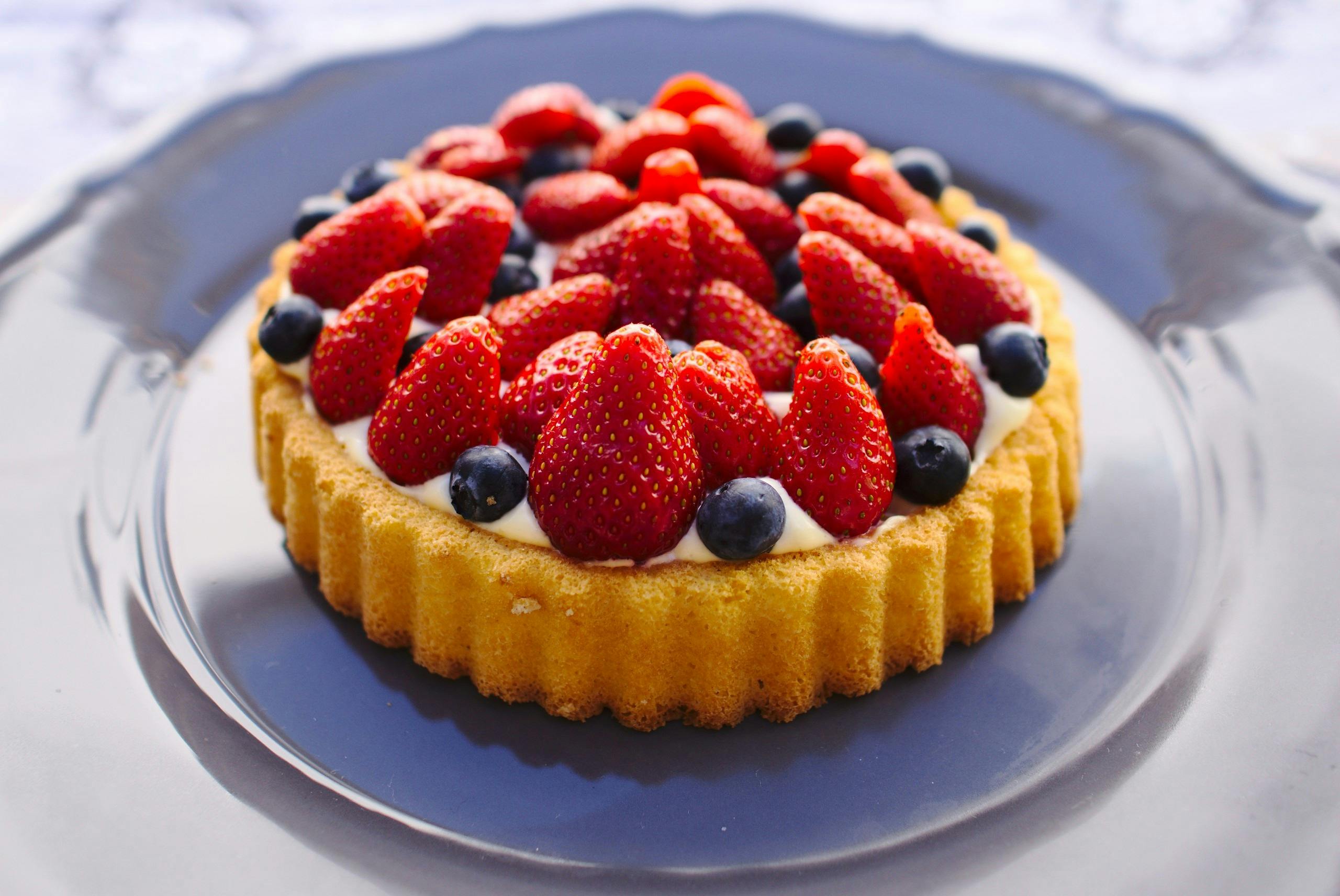 Cream cheese dessert recipe featuring a golden tart topped with a creamy layer and a vibrant arrangement of fresh strawberries and blueberries